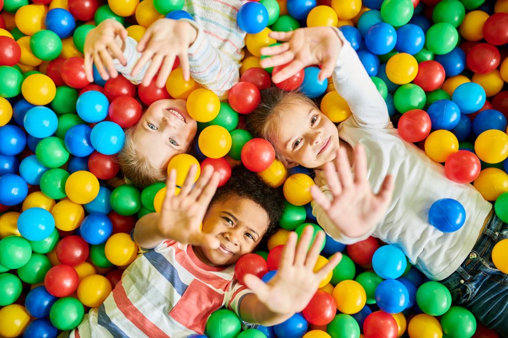 three kids playing in ballpit