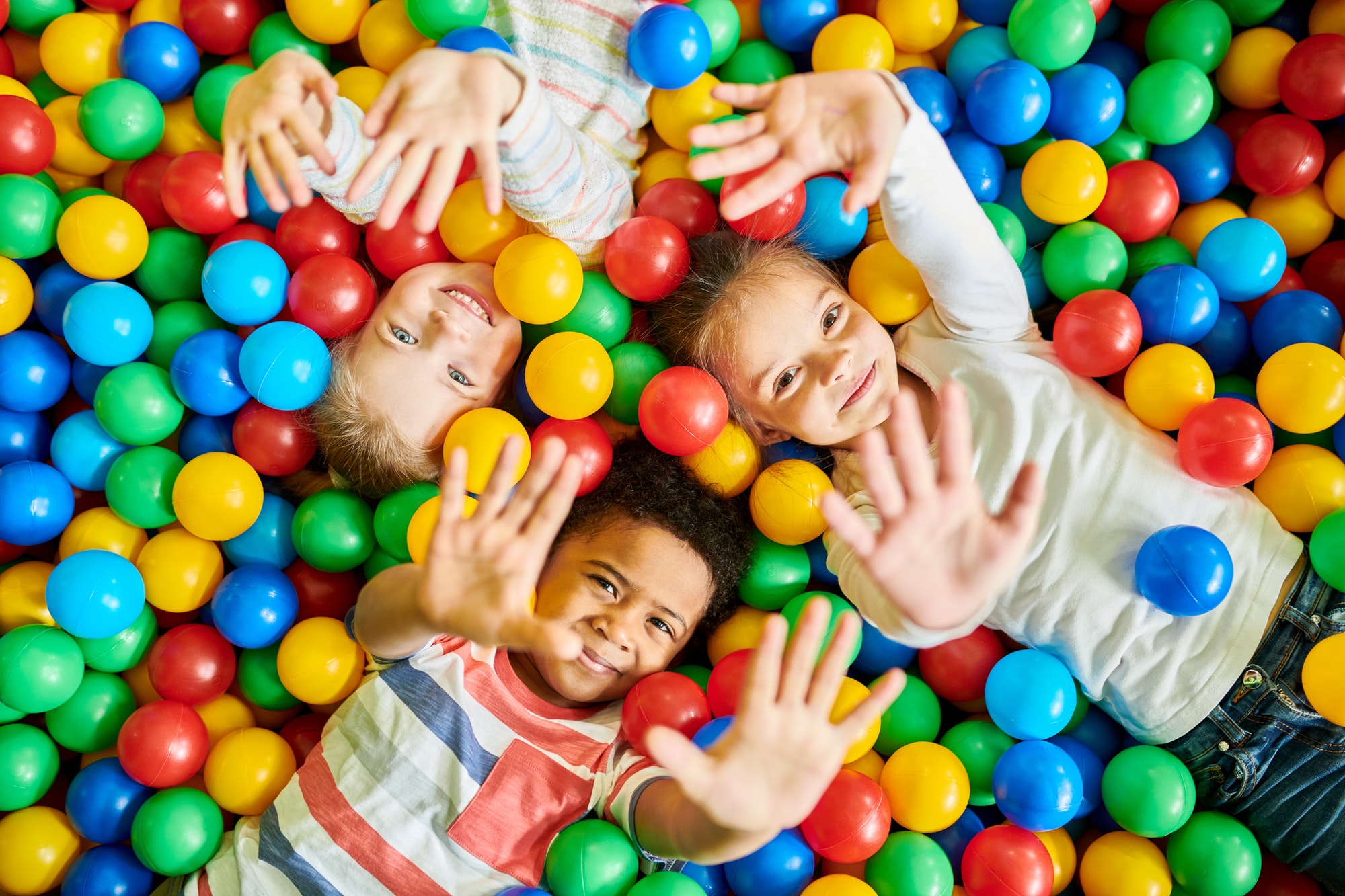 three kids playing in ballpit