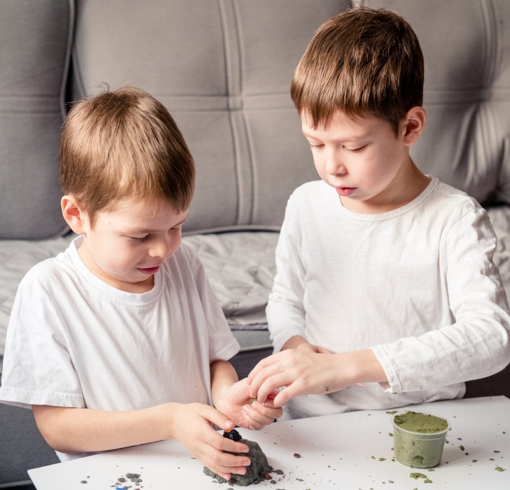 children play with loose sand at home. Development of fine motor skills.