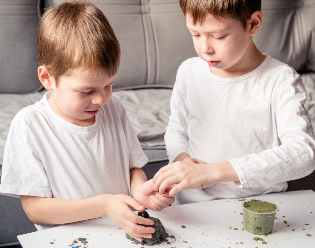 children play with loose sand at home. Development of fine motor skills.