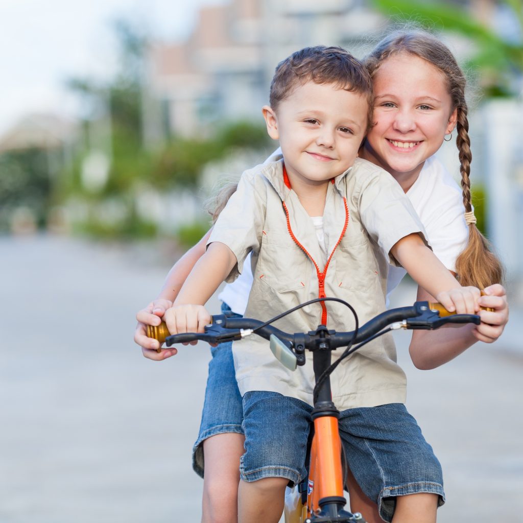 Happy kids with bike standing on the road at the day time.