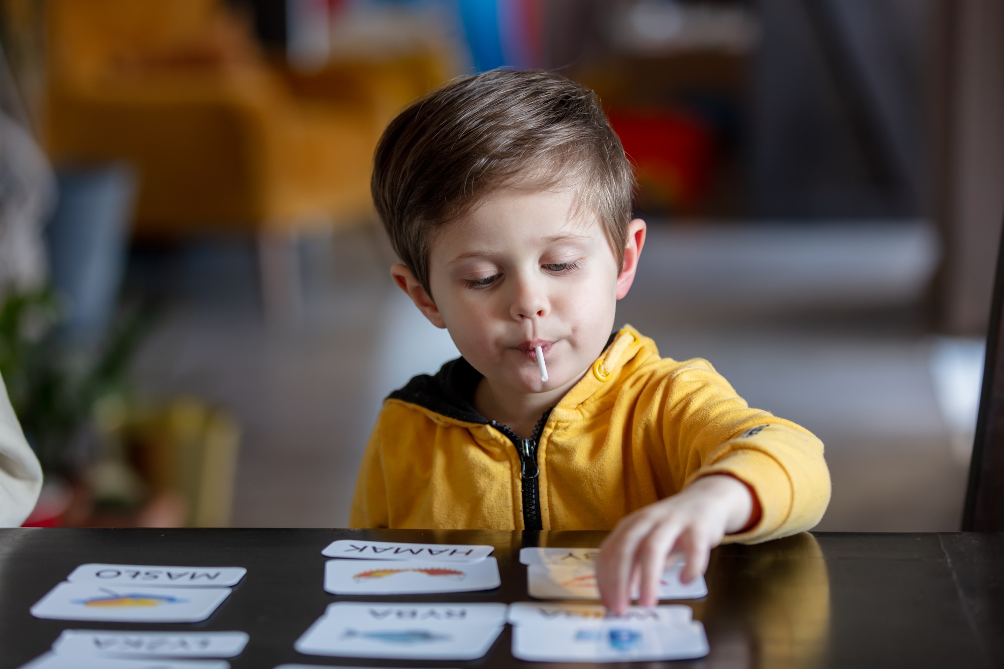 little boy learns words from cards under the ABA therapy program at home at the table