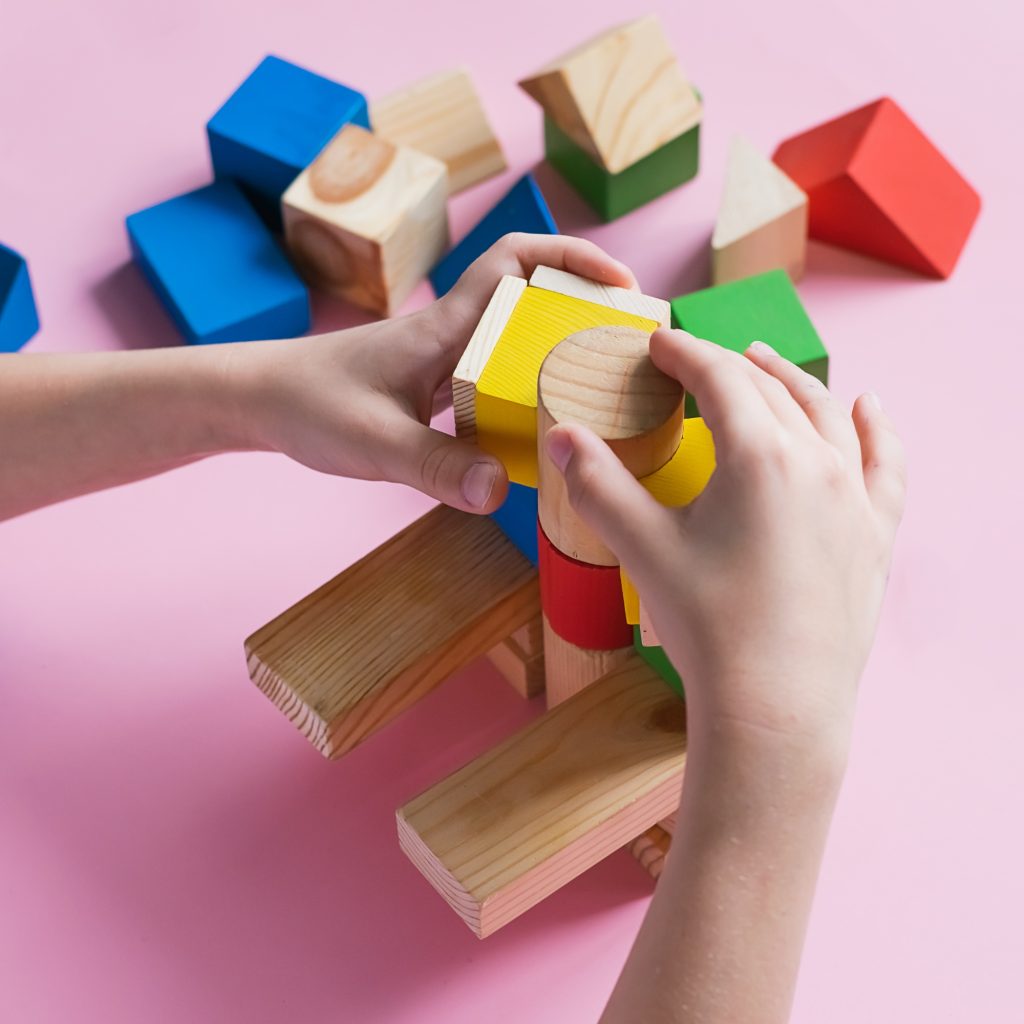 Little kid plays assemble with wooden cubes constructor. Education concept for children learning