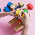 little kid plays assemble with wooden cubes constructor education concept for children learning