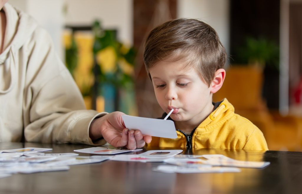 little boy learns words from cards under the ABA therapy program at home at the table