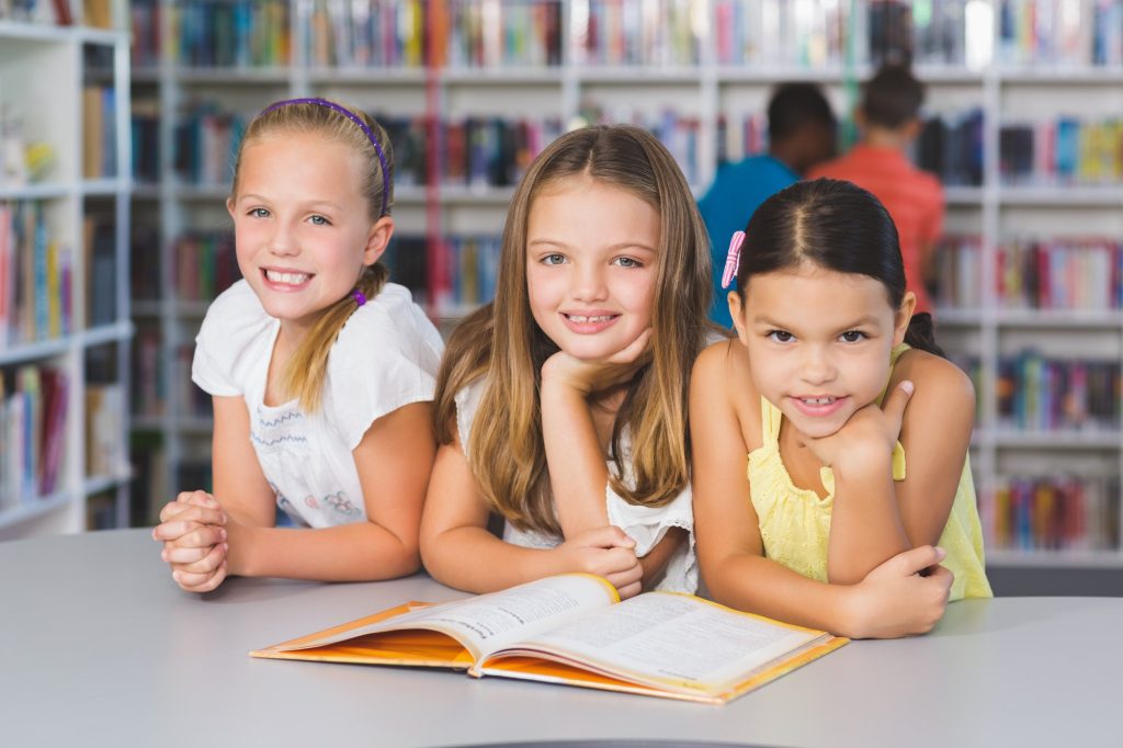 school kids reading book together in library