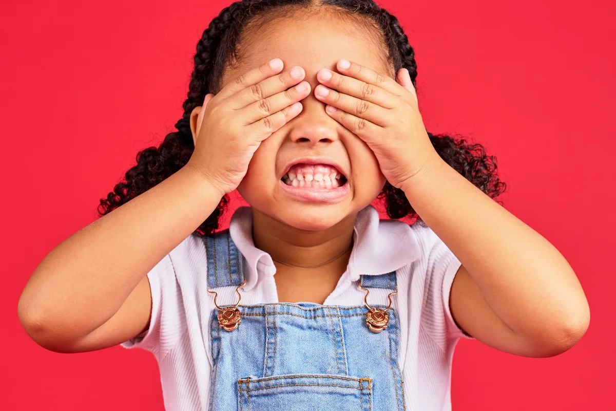 Child covering their eyes and turning away, showing signs of sensory overload rather than misbehavior