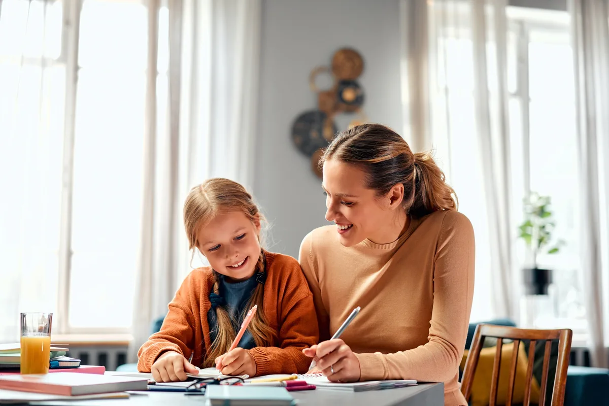 Parent sitting calmly beside their child at a table, using supportive strategies to help them regulate