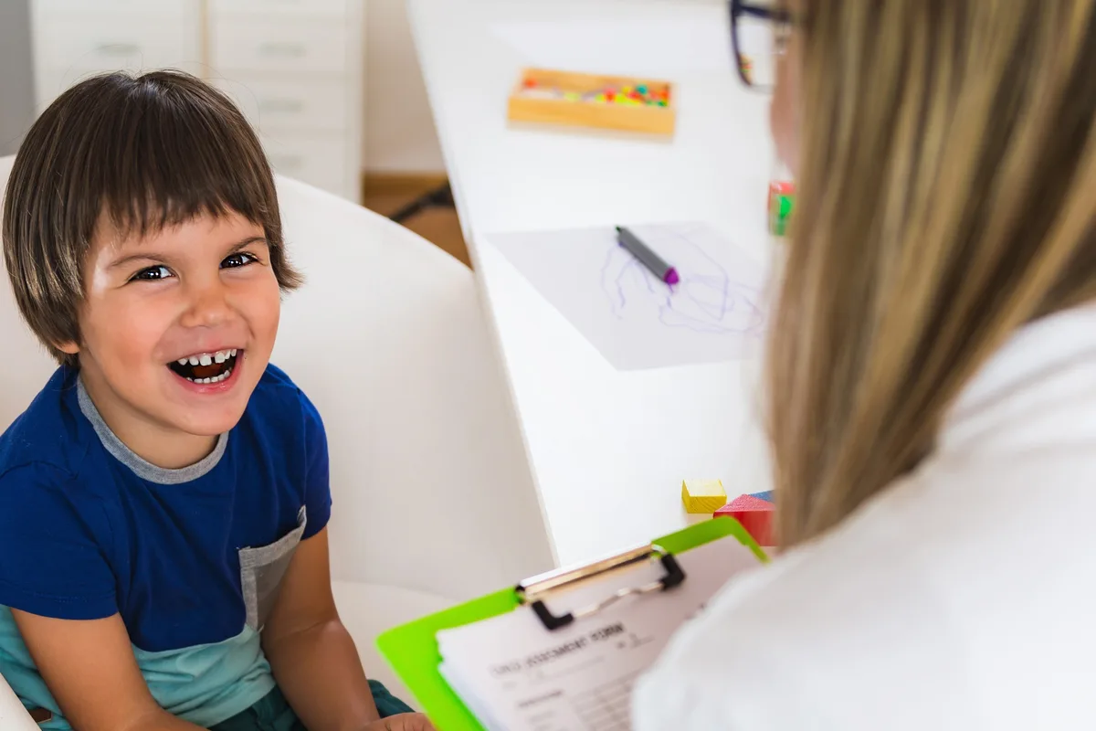 Smiling child next to a professional taking notes on a clipboard