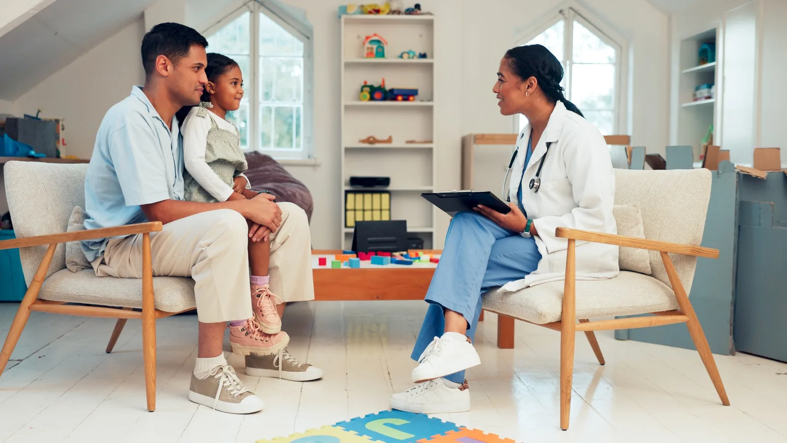 Padre e hijo sentados con una profesional de la salud que revisa informacion en una tableta