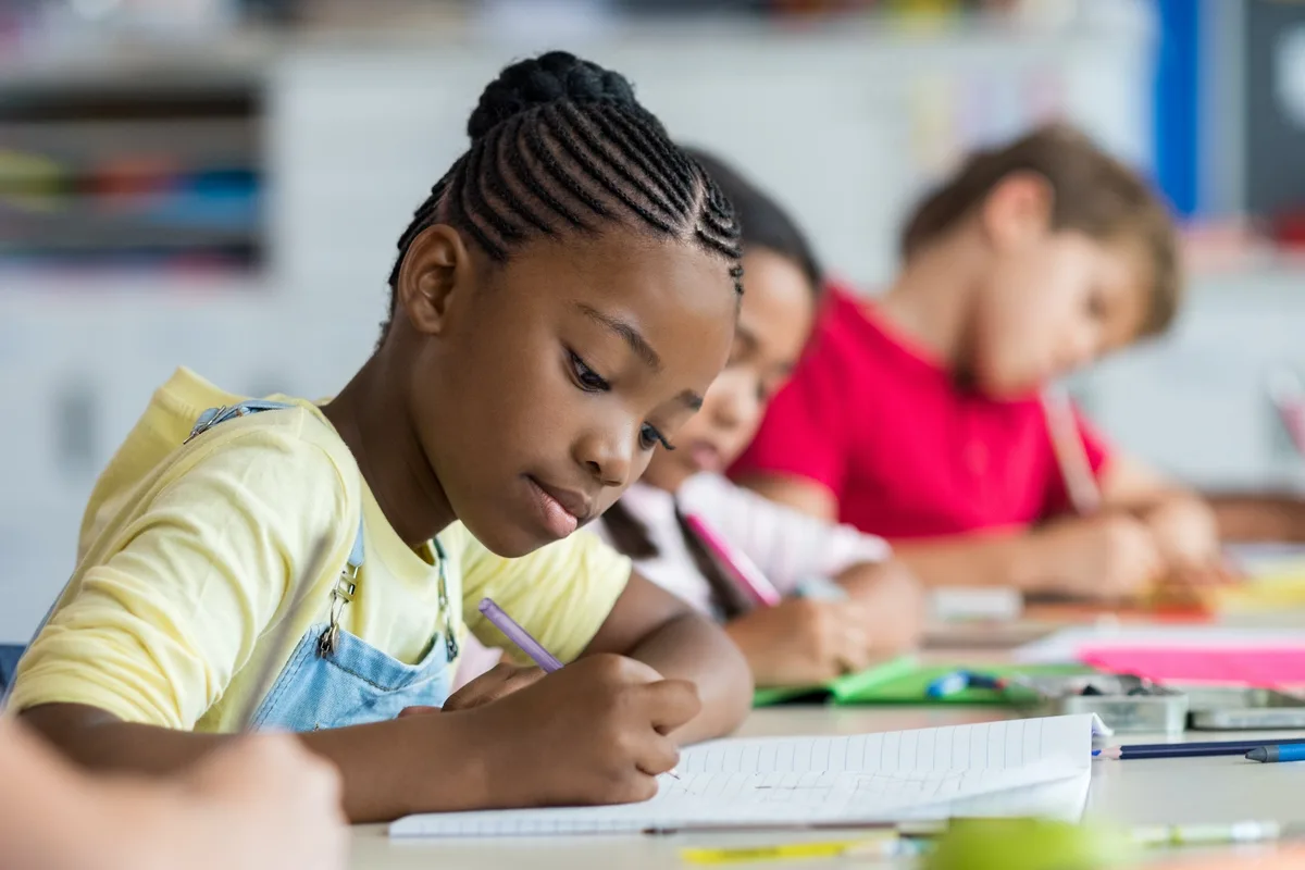 Students writing at their desks during class, focused on their work